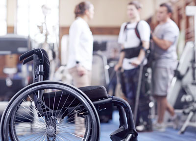 Man receiving physical therapy with wheelchair in foreground